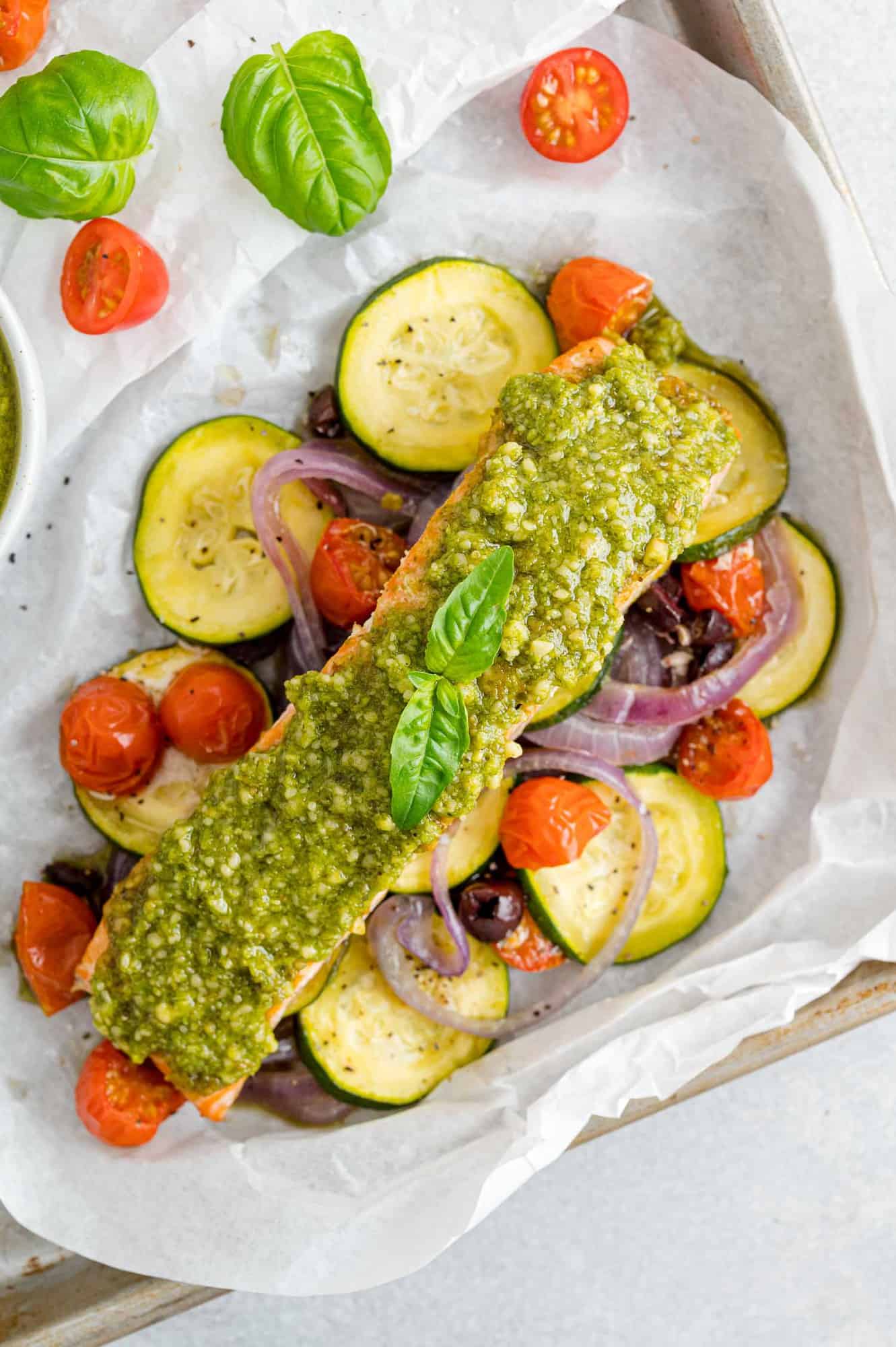 Overhead view of pesto salmon in parchment paper with vegetables.