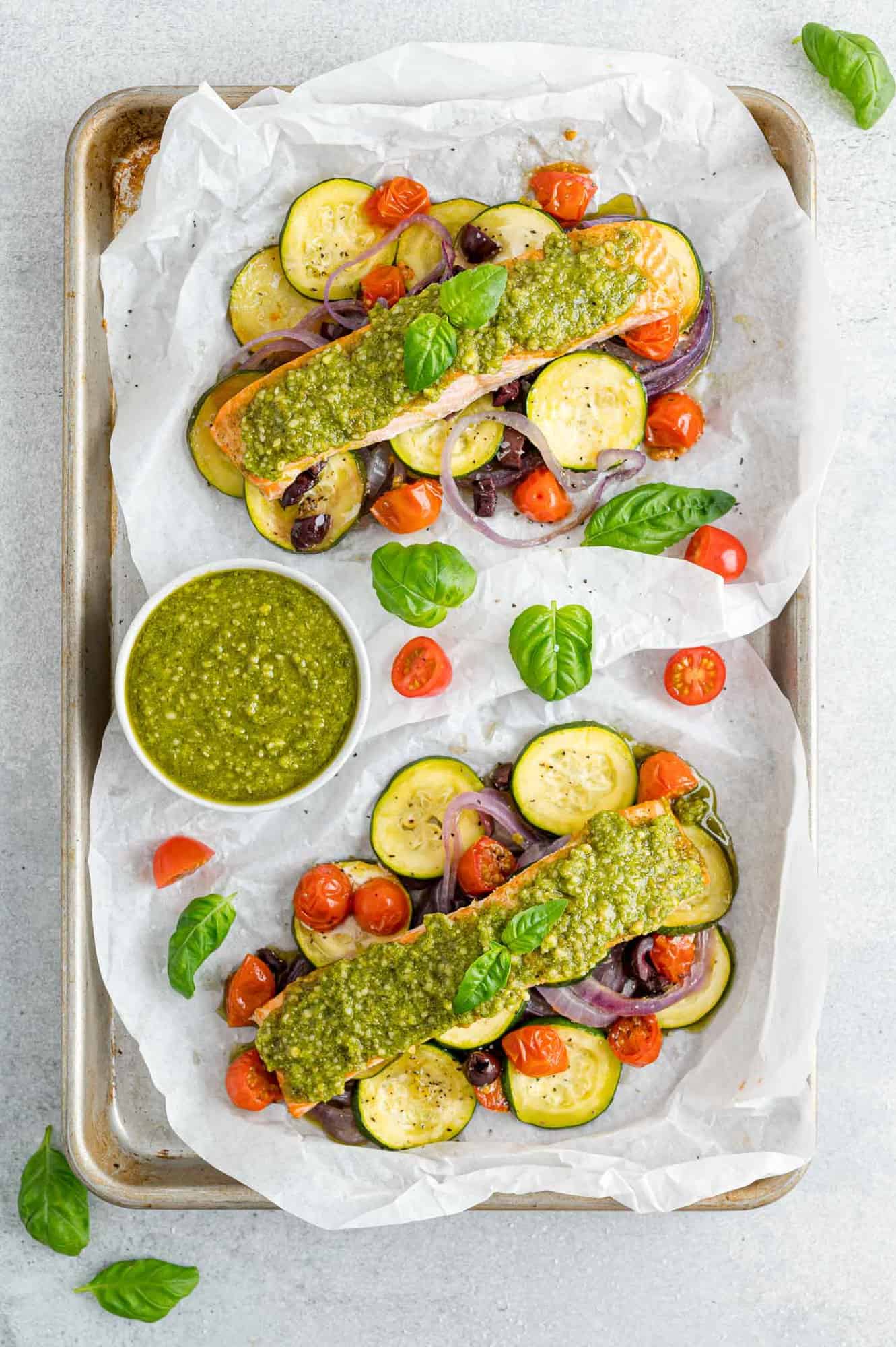 Overhead view of two open packets of pesto salmon with vegetables.