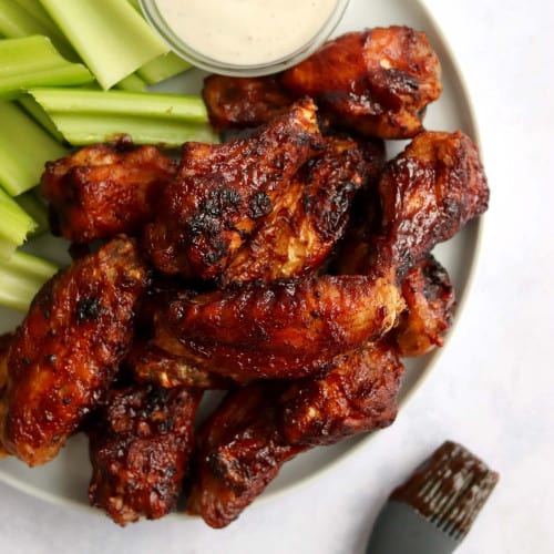 Air fryer barbecue chicken wings on a plate with celery and dip.