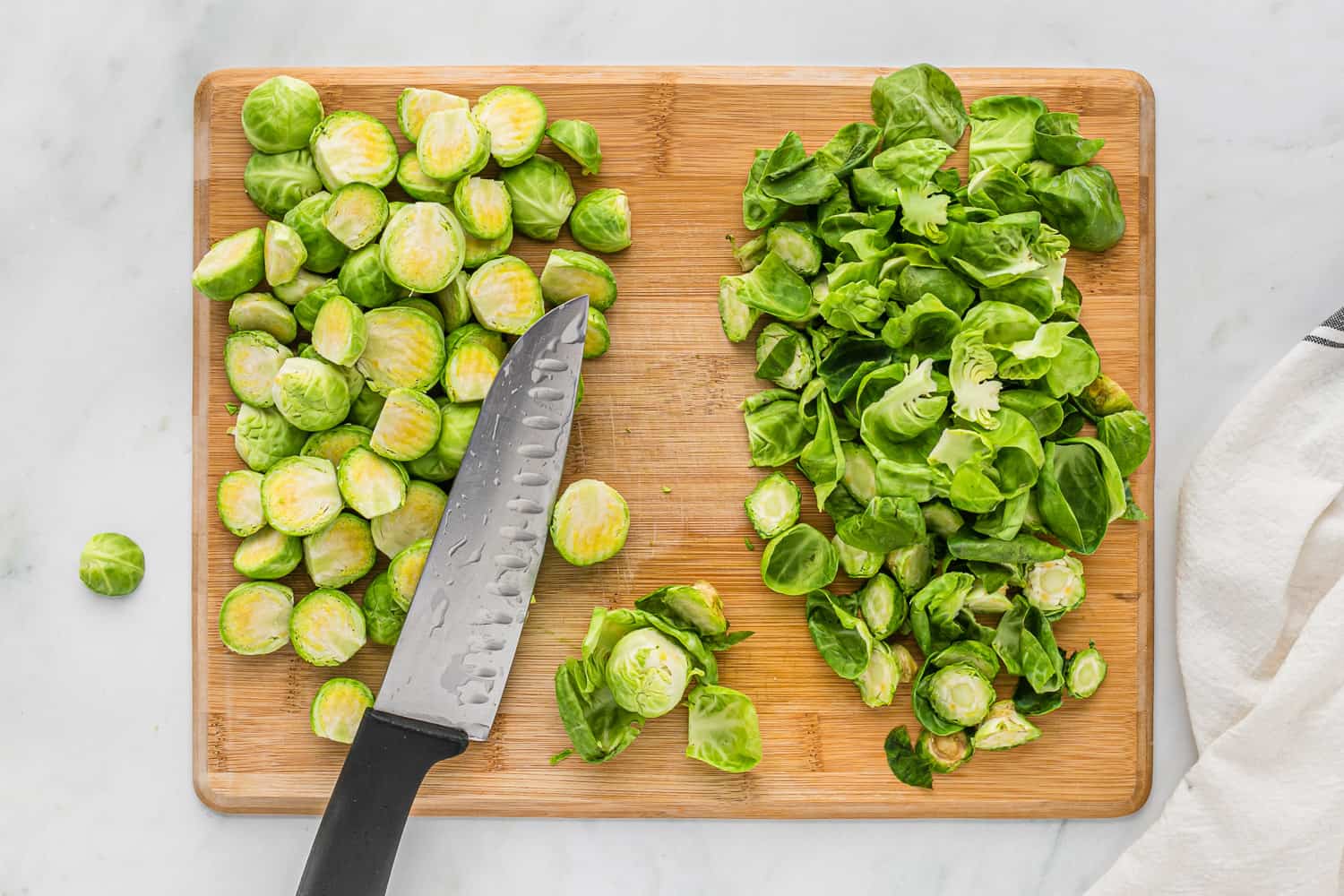 Brussel sprouts, trimmed, knife on cutting board.