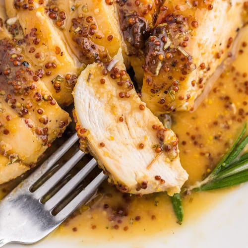 Slice of chicken on a fork with honey mustard sauce.