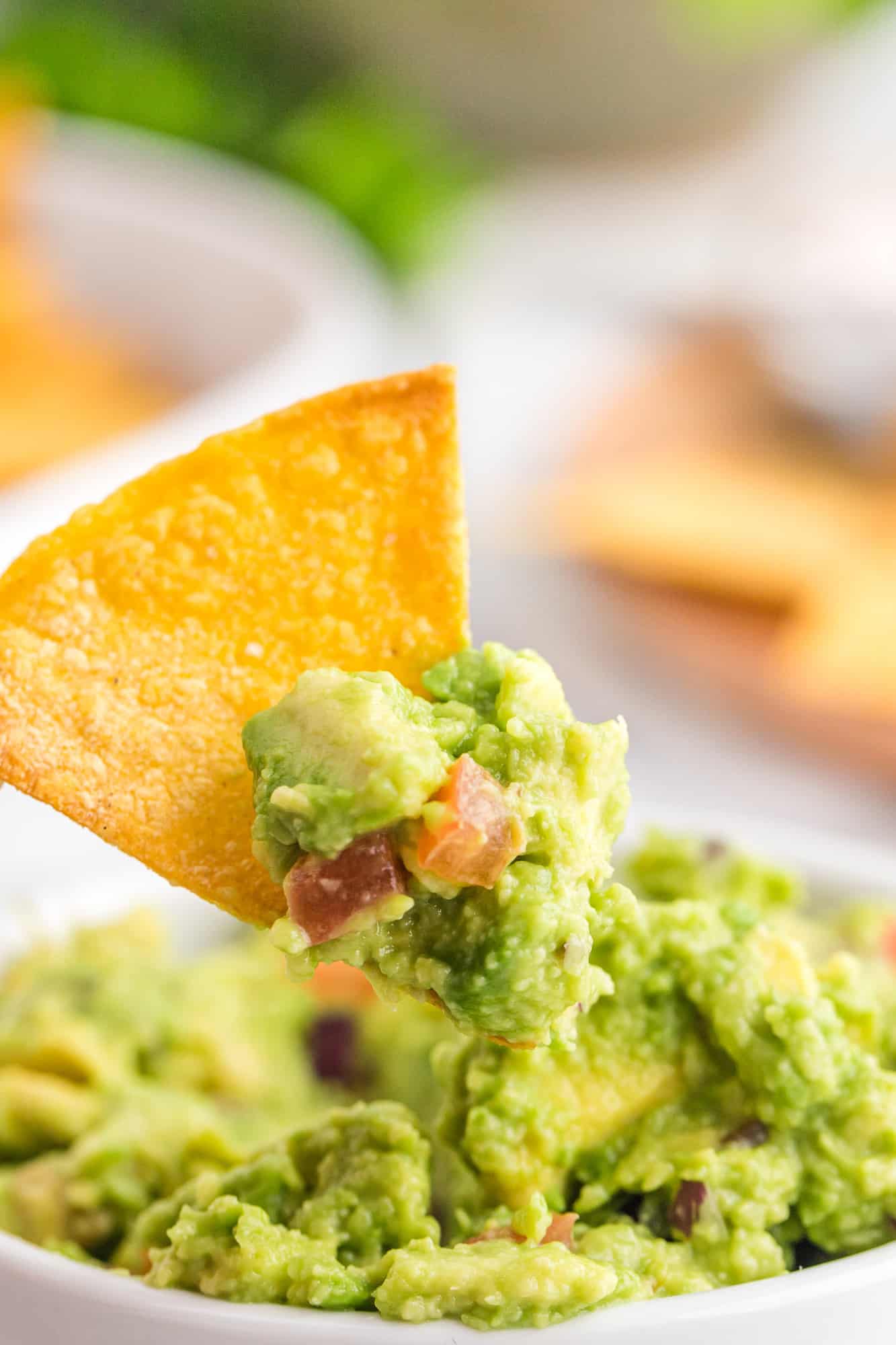 Homemade tortilla chip being dipped in guacamole.