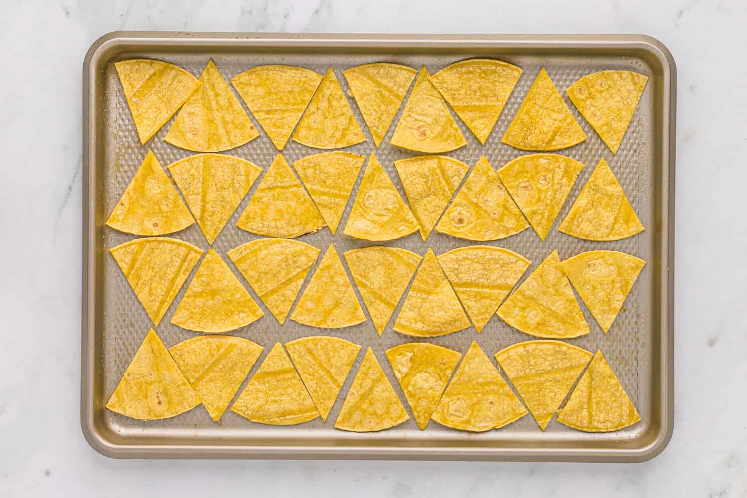 Unbaked tortilla wedges on a baking sheet.