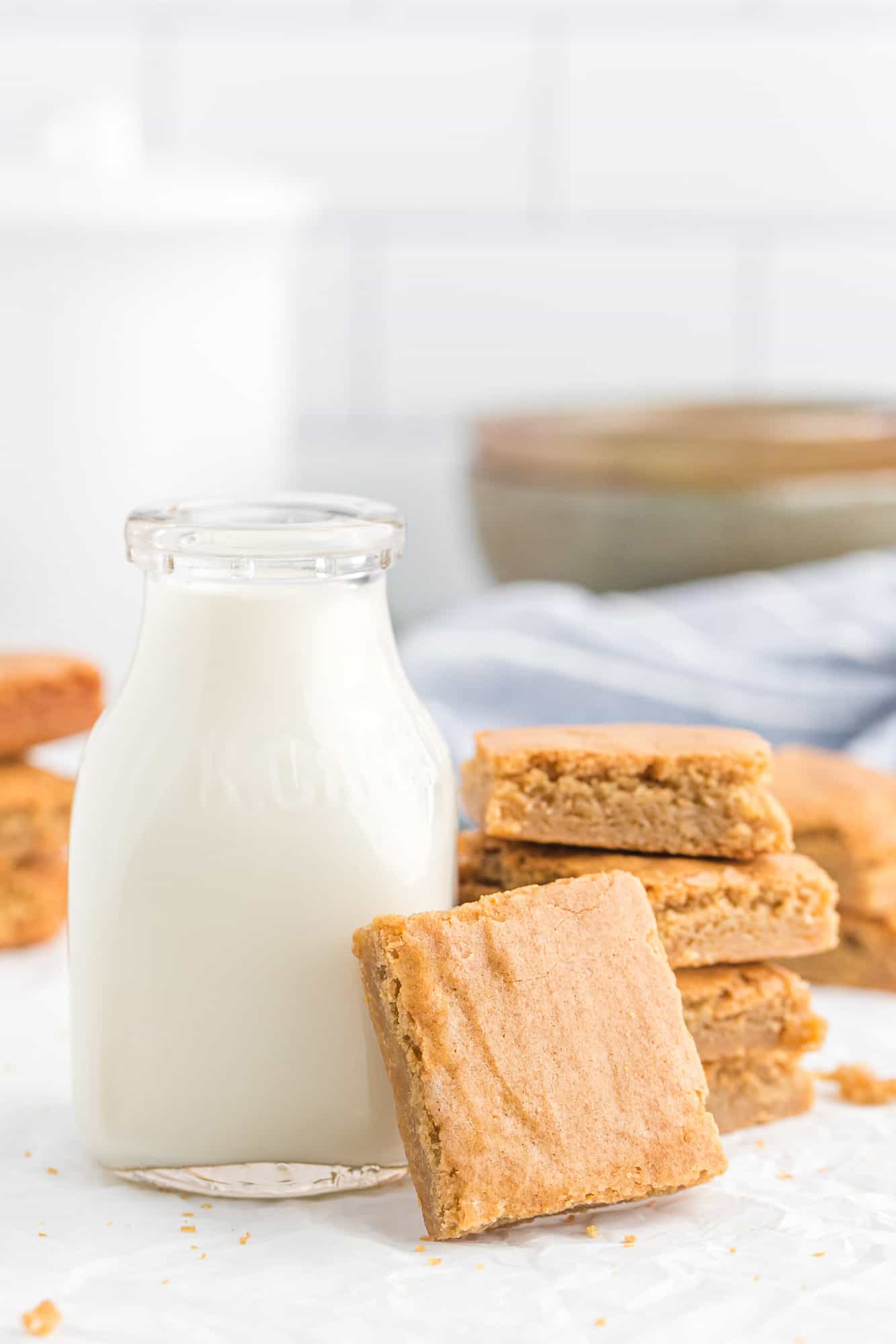 Blondies stacked by a small jug of milk.