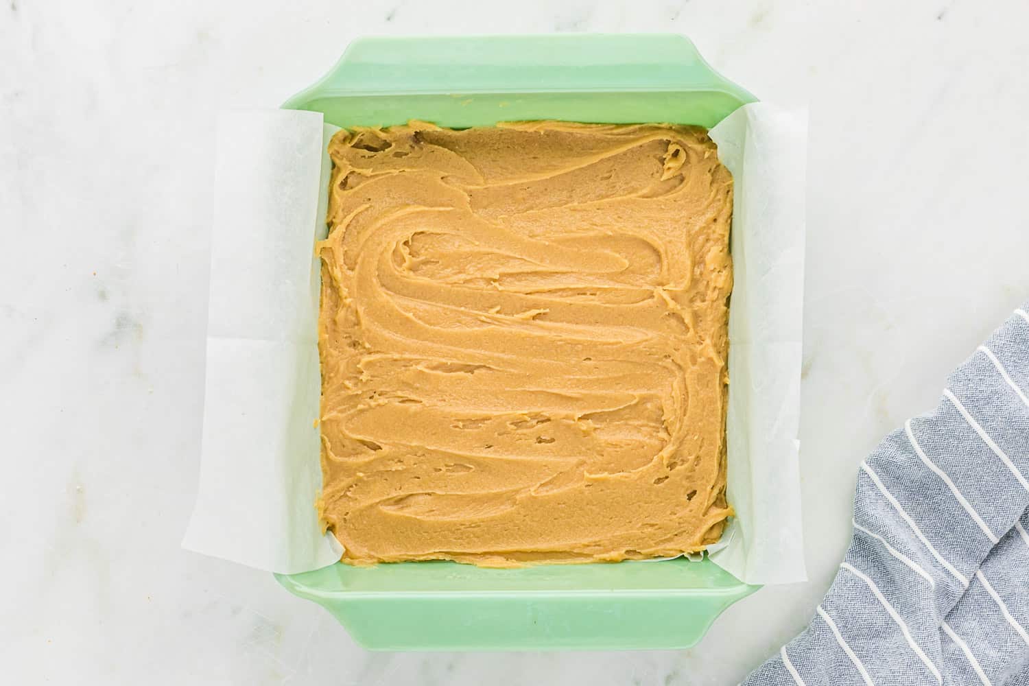 Unbaked blondie recipe in a green pan.