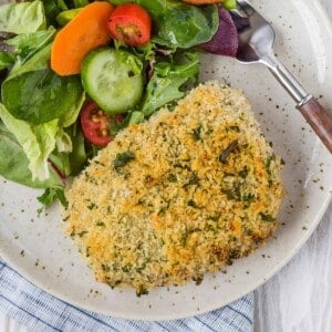 Overhead view of breaded pork on a plate with green salad.
