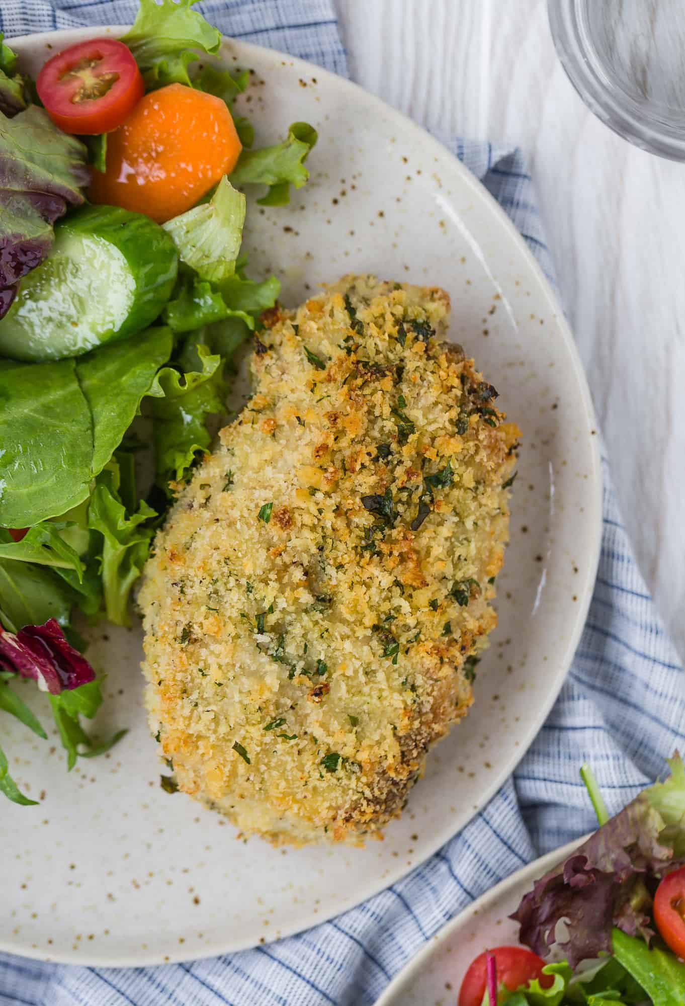 Breaded pork chop on a plate with a simple green salad.