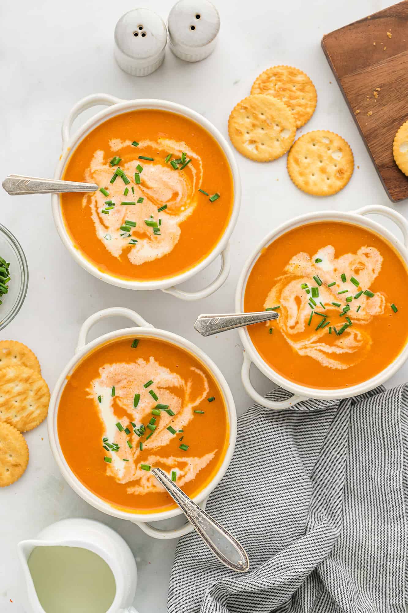 Three bowls of creamy carrot soup with spoons.