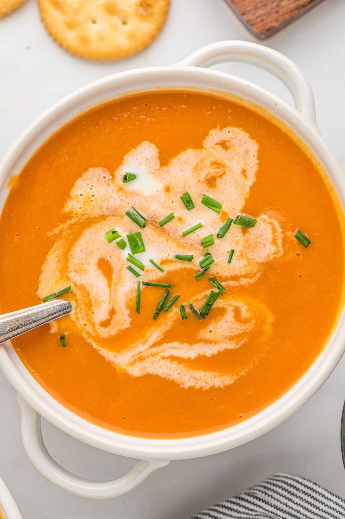 Creamy carrot soup swirled with cream and topped with chives.