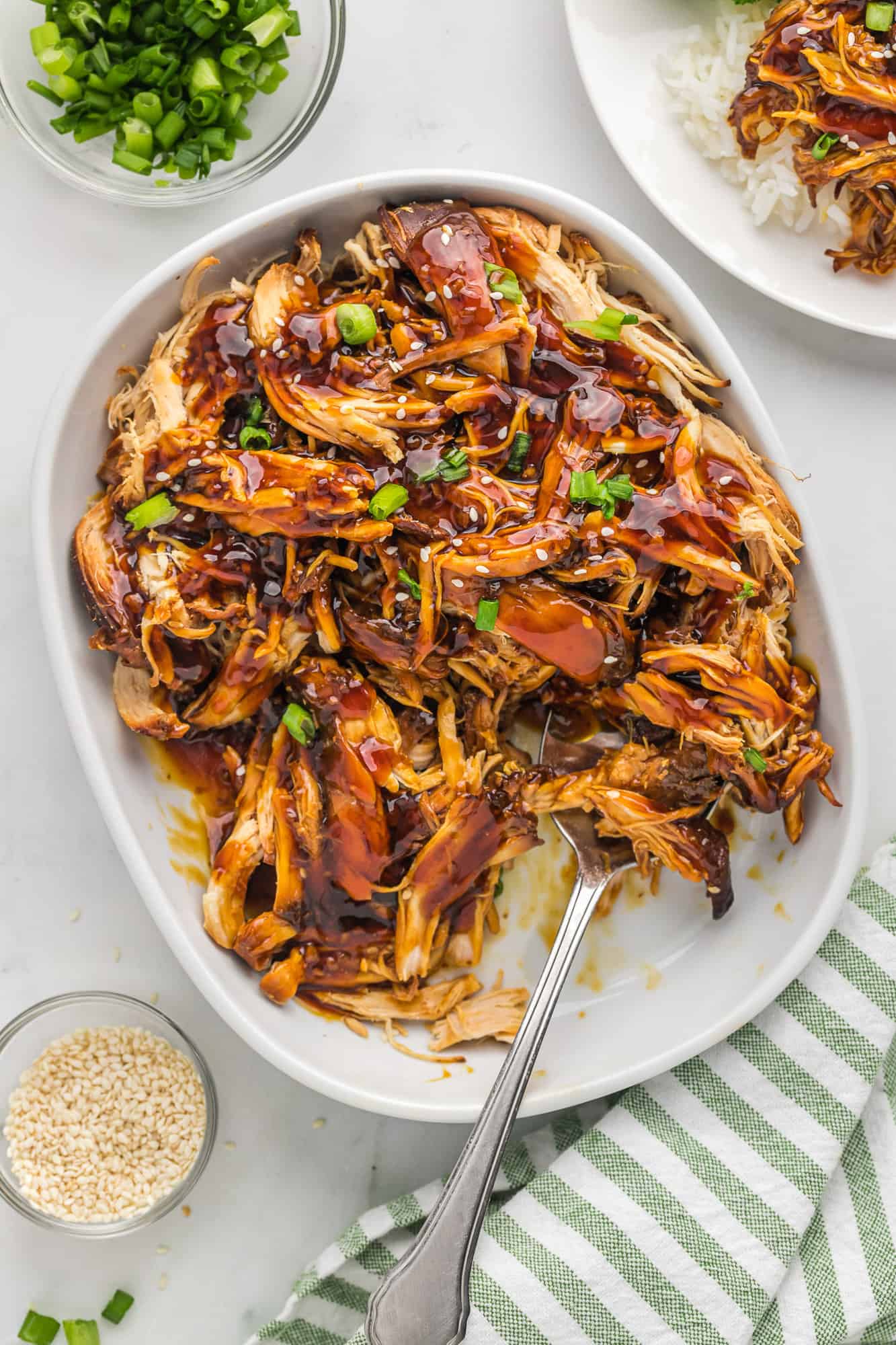 Teriyaki chicken in a serving dish with a large spoon.