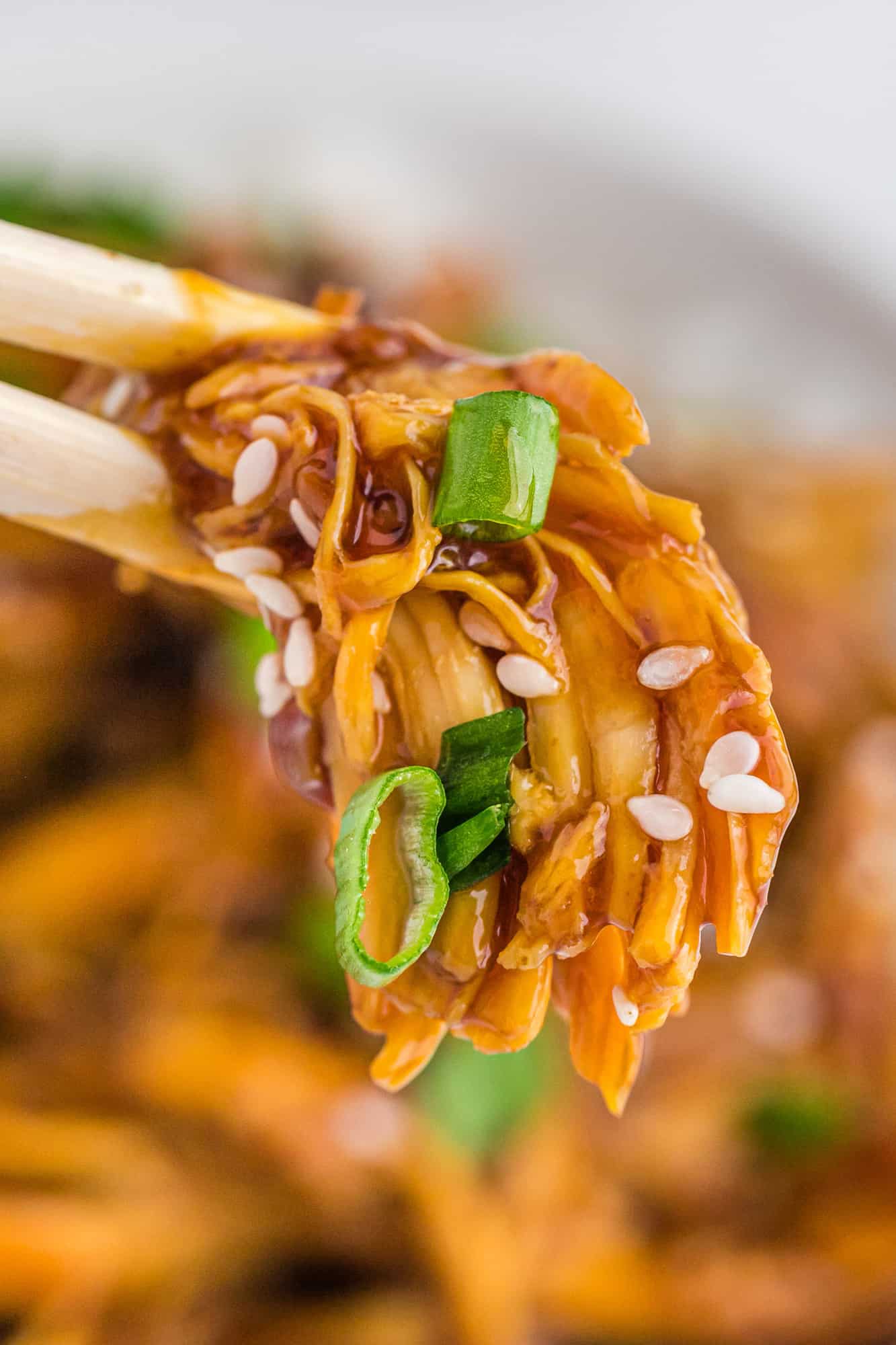 Crockpot chicken teriyaki between chopsticks.