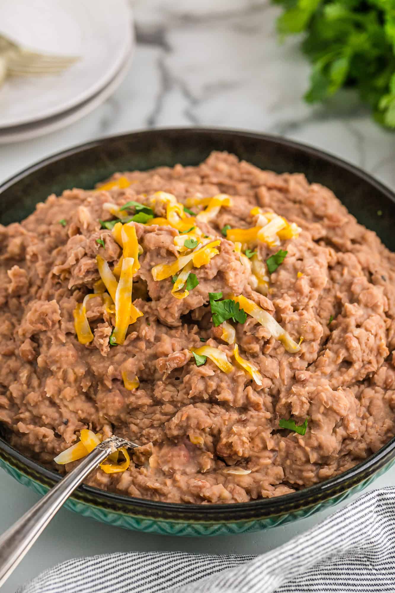 Crockpot refried beans topped with cheese and cilantro.