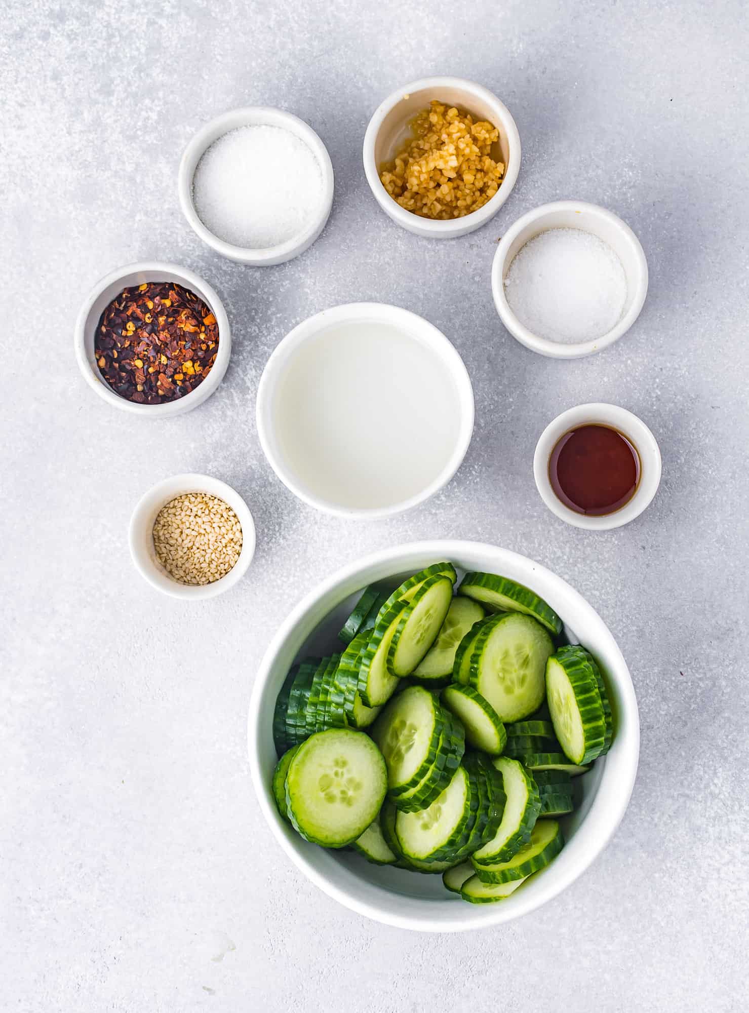 Ingredients needed in separate bowls including sliced cucumber.