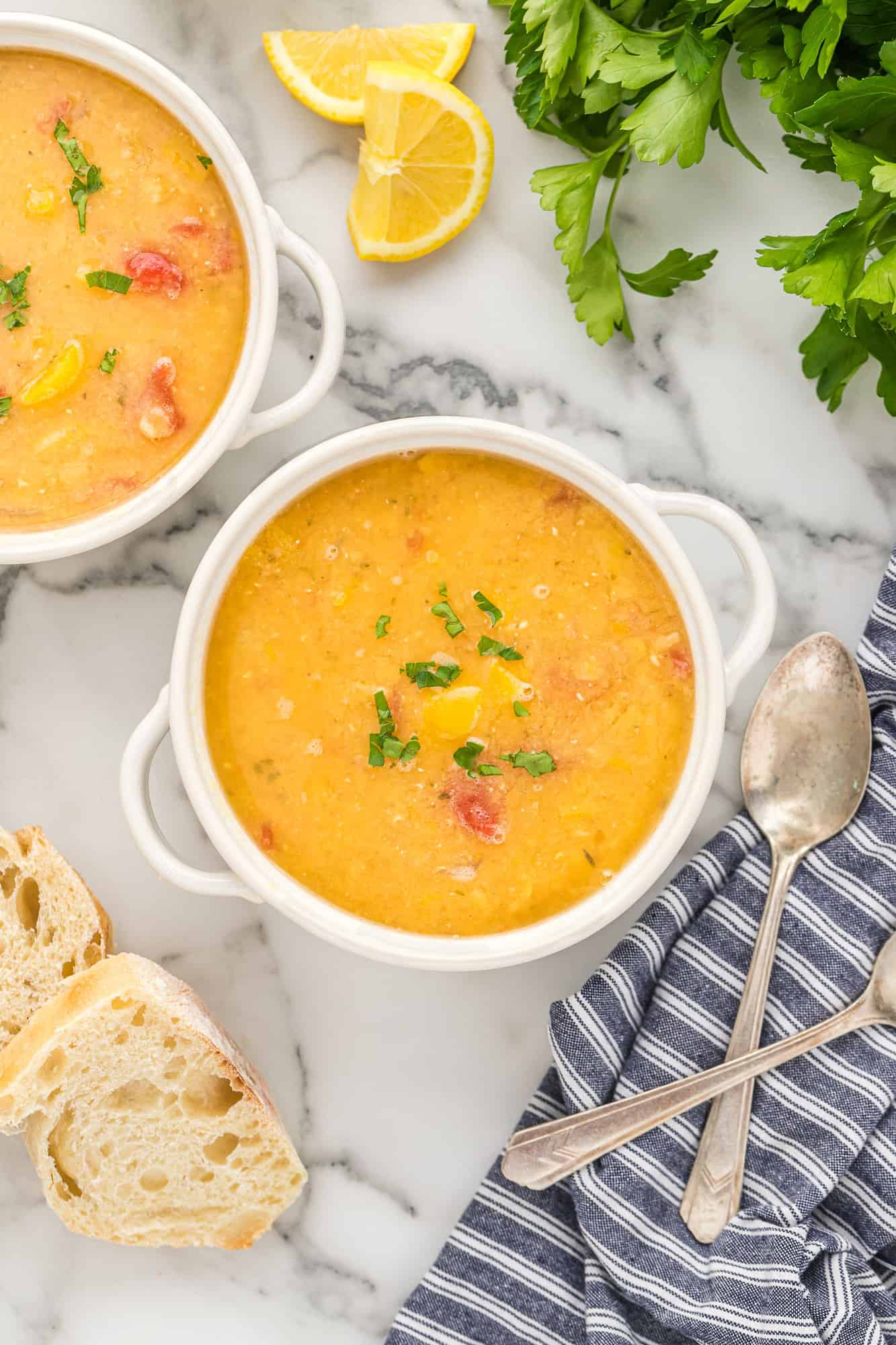 Overhead view of two bowls of red lentil soup and bread.