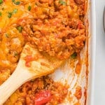 Stuffed pepper casserole being scooped out with a wooden spoon.