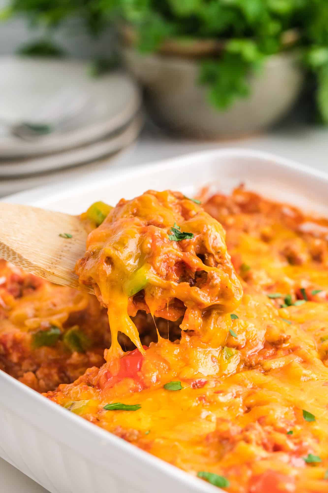 Stuffed pepper casserole being scooped out of a white casserole dish.