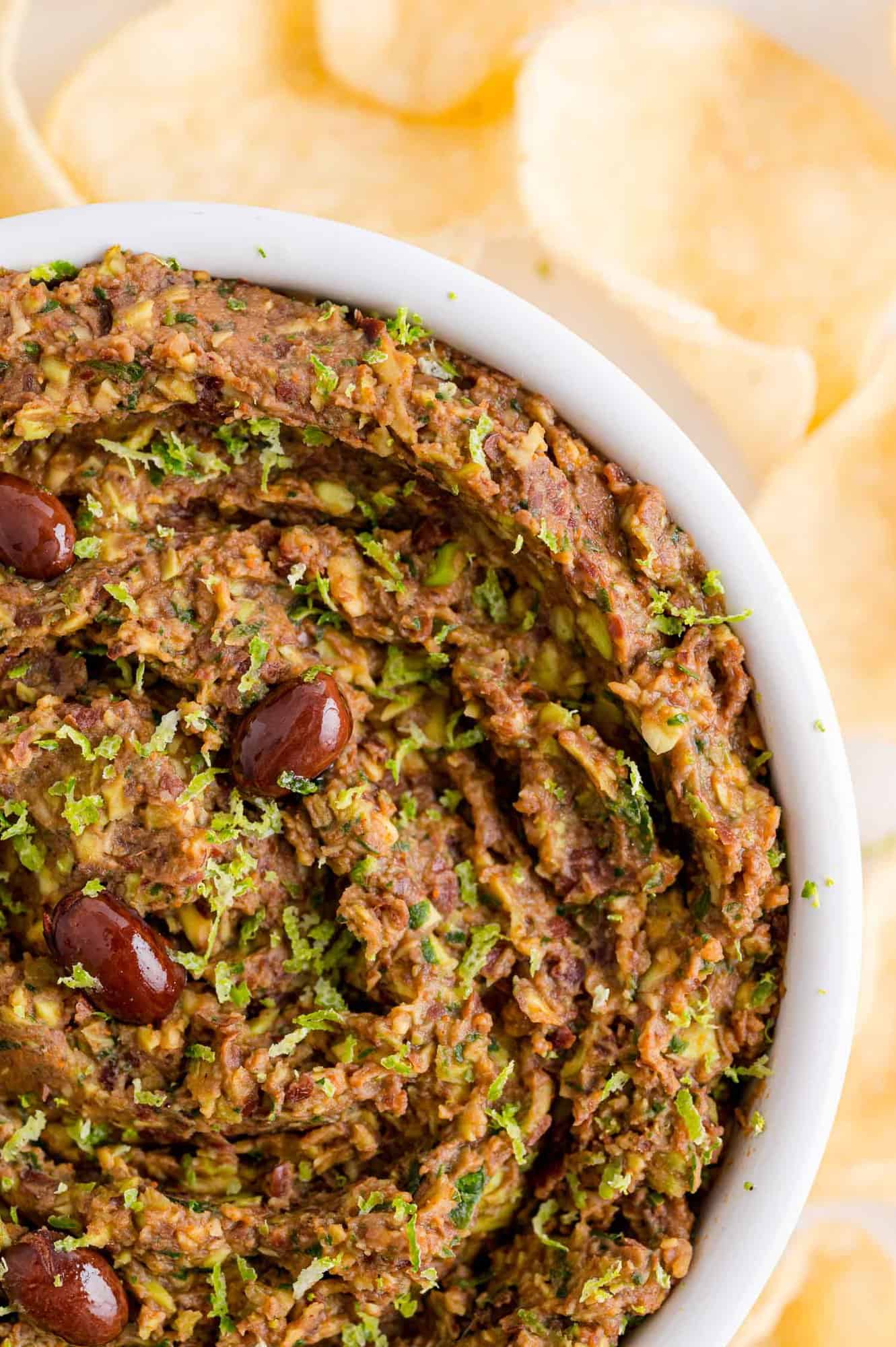 Bean dip in a white bowl surrounded by tortilla chips.