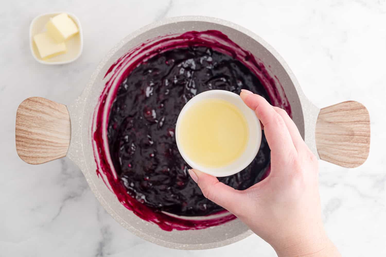 Lemon juice being added to blueberry mixture.