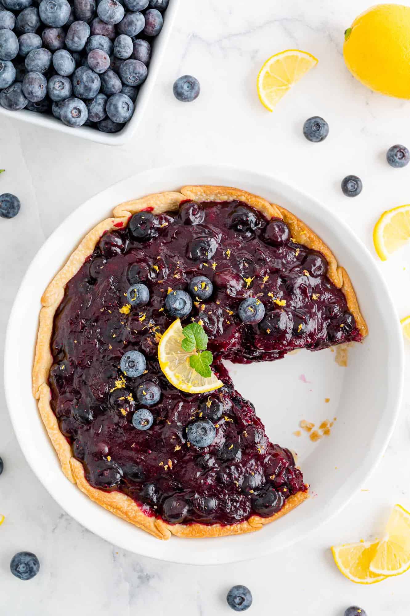 Overhead view of fresh blueberry pie with a slice removed.