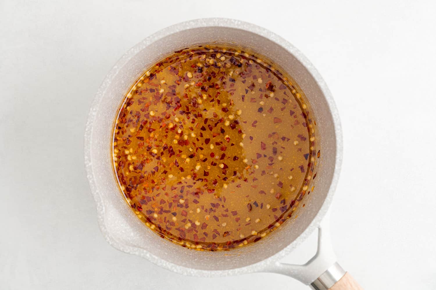 Honey with red pepper flakes in a saucepan.
