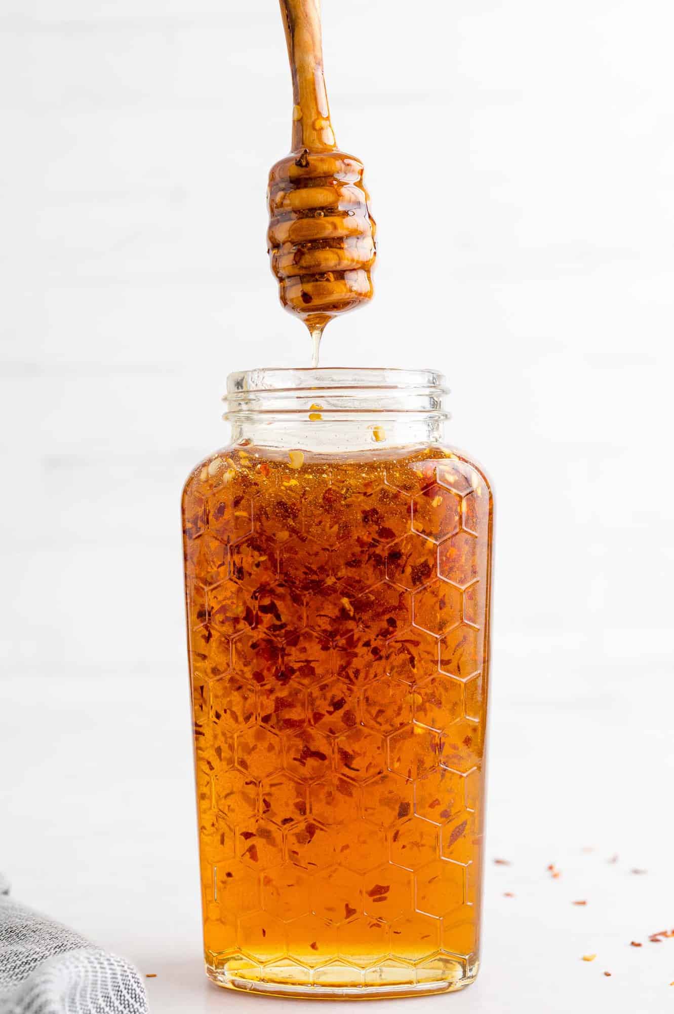 Hot honey in a jar with a honey dipper being lifted out.