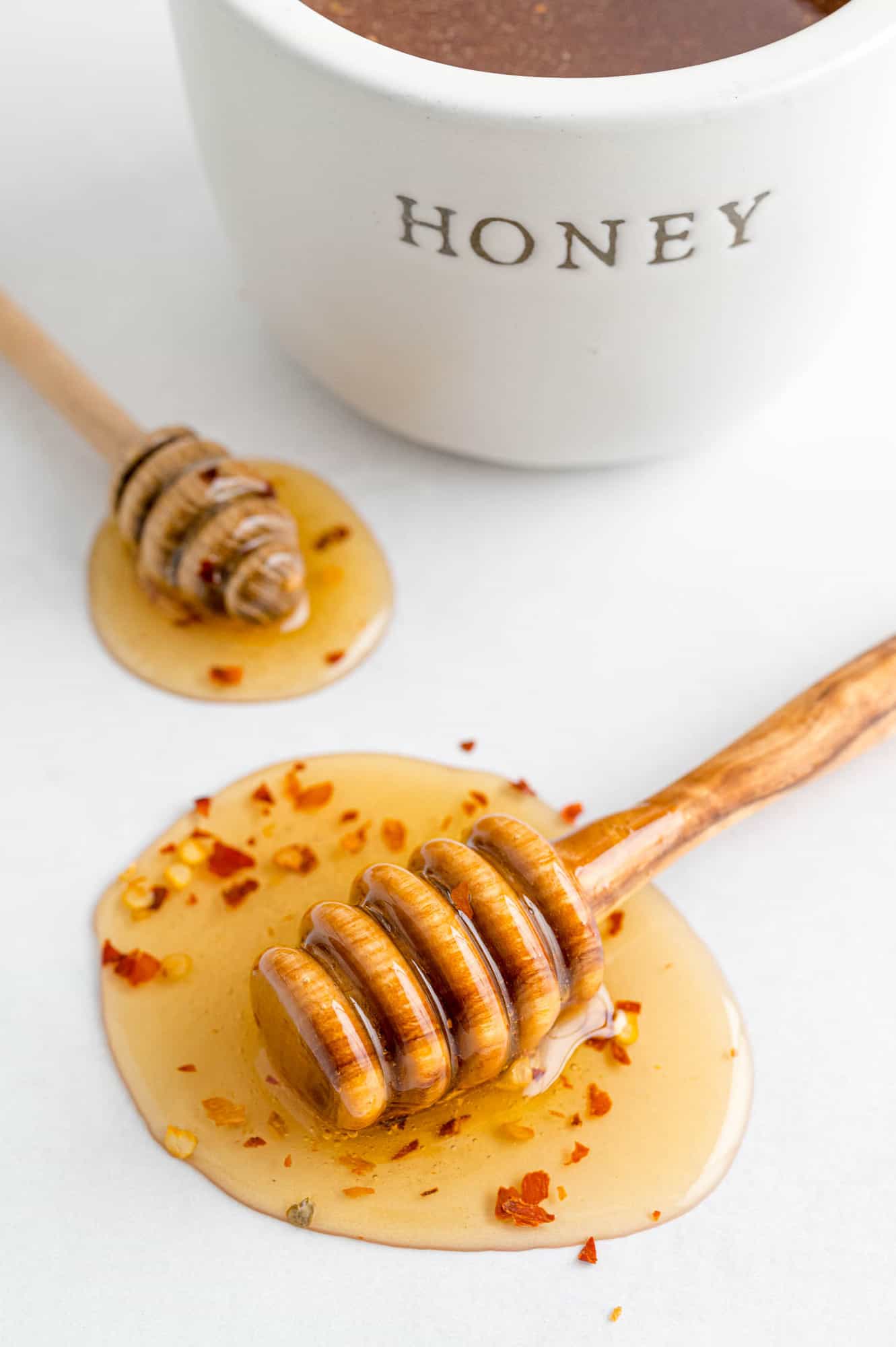 Honey with red pepper flakes on a white surface.