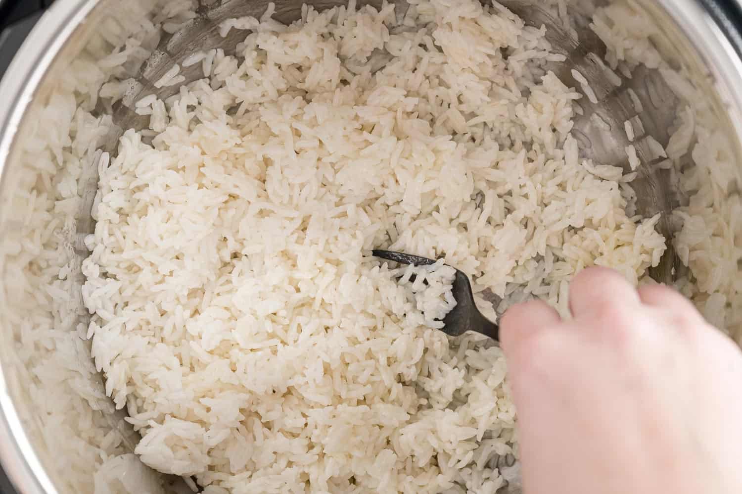 Rice being fluffed with a fork.