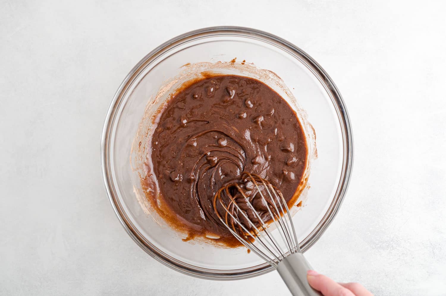 Brownie batter in a clear glass mixing bowl.