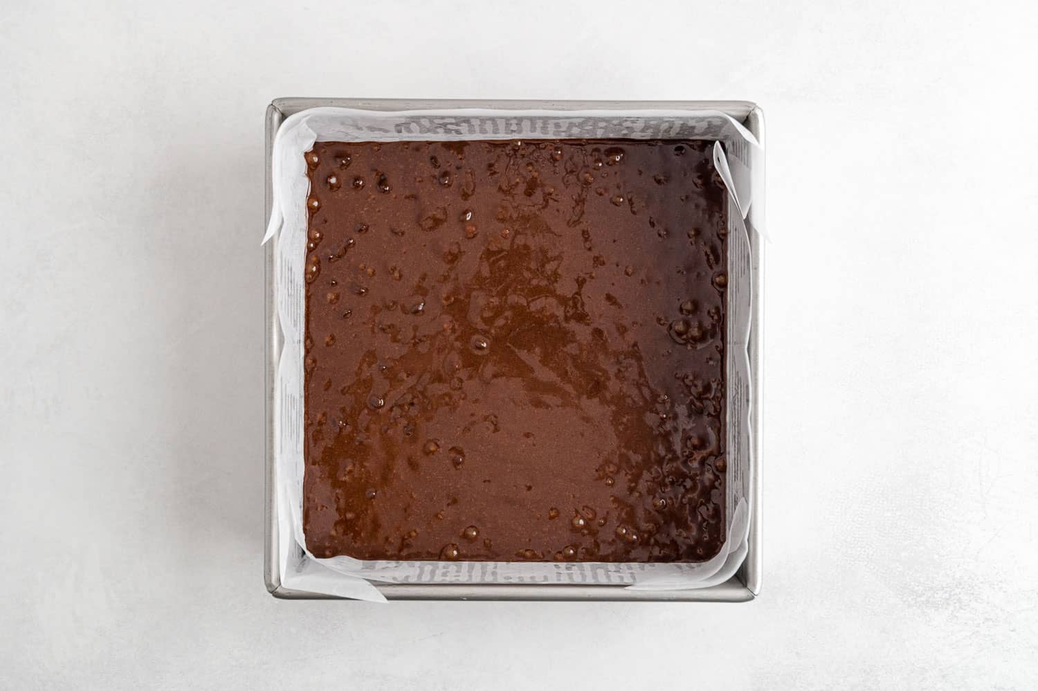 Unbaked brownies in a square dish.