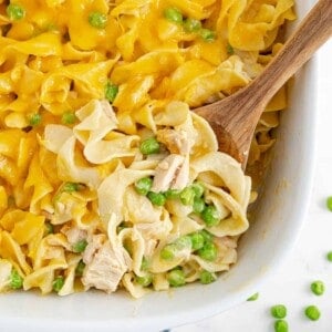Tuna casserole in a white baking dish with a wooden spoon.