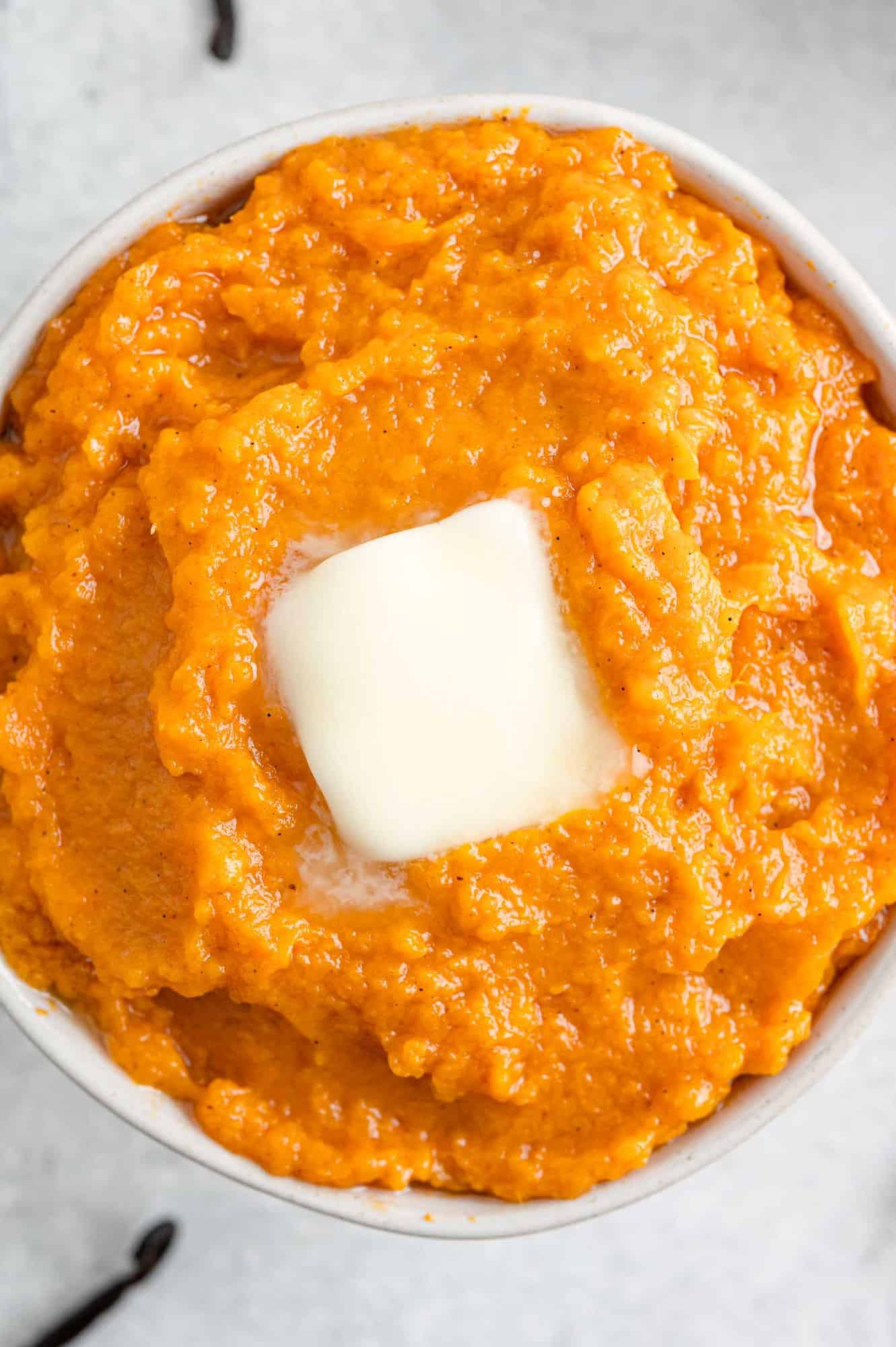 Close up of mashed sweet potatoes topped with butter.