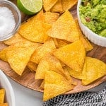 Baked tortilla chips on a wooden platter.