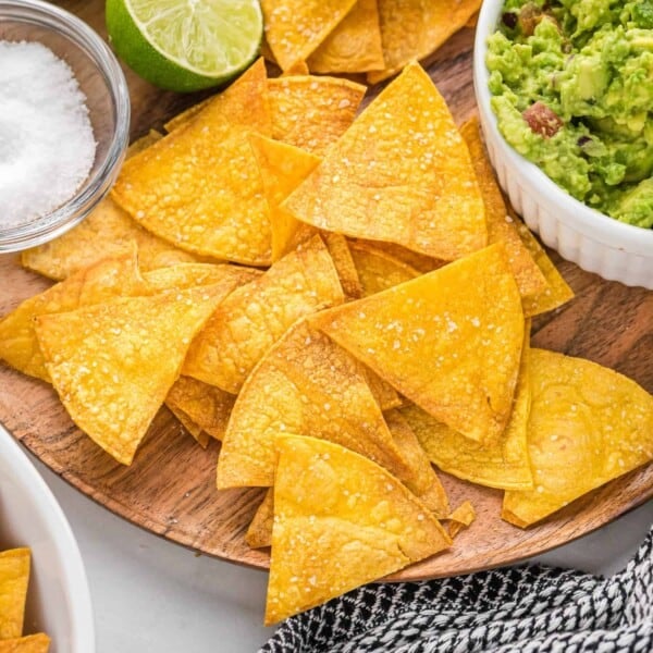 Baked tortilla chips on a wooden platter.