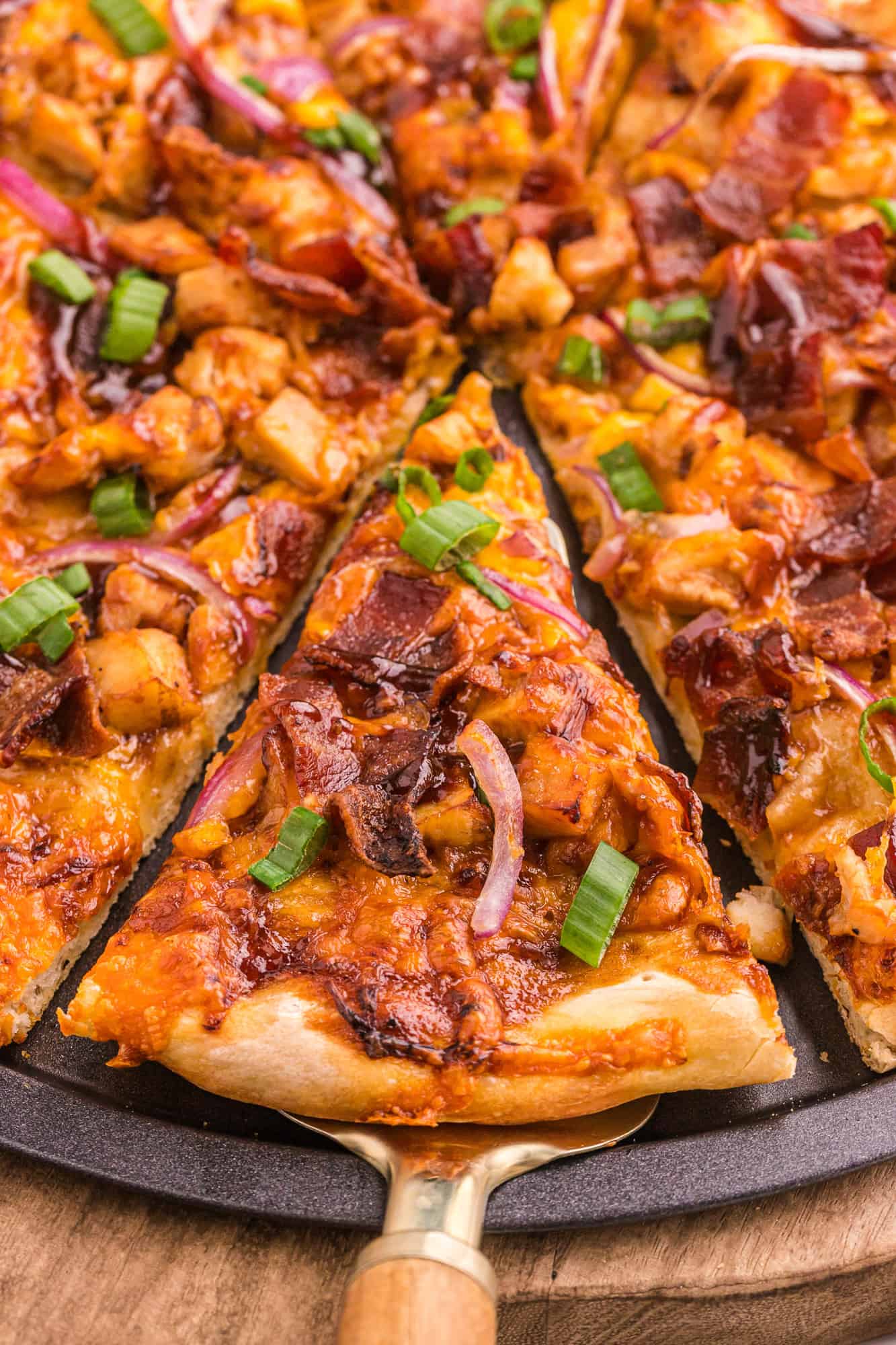 Slice of bbq chicken pizza being removed from pan.