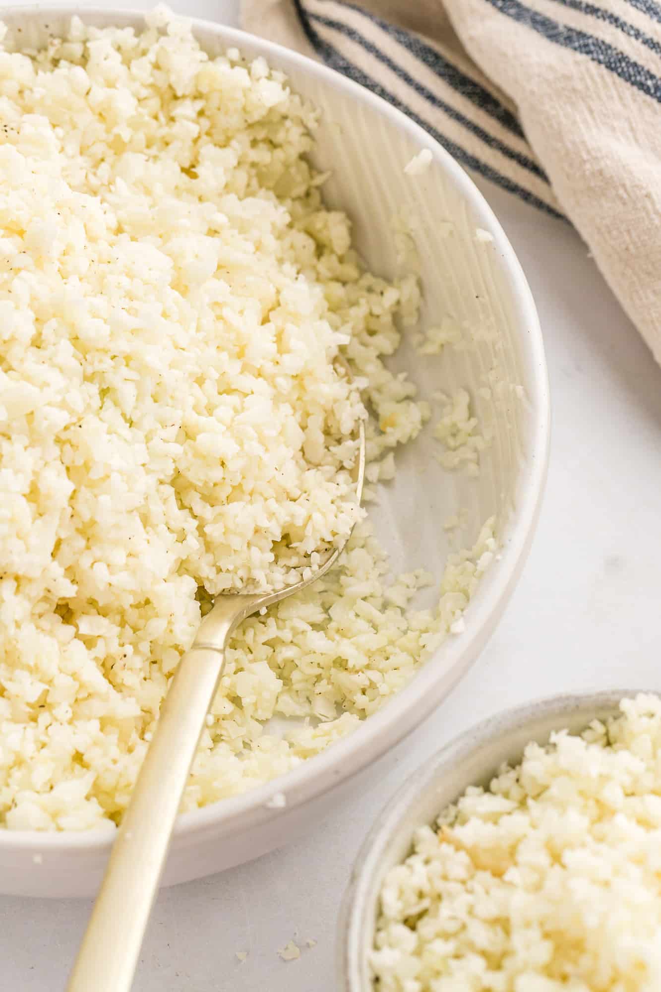 Cauliflower rice in a serving bowl with a spoon.