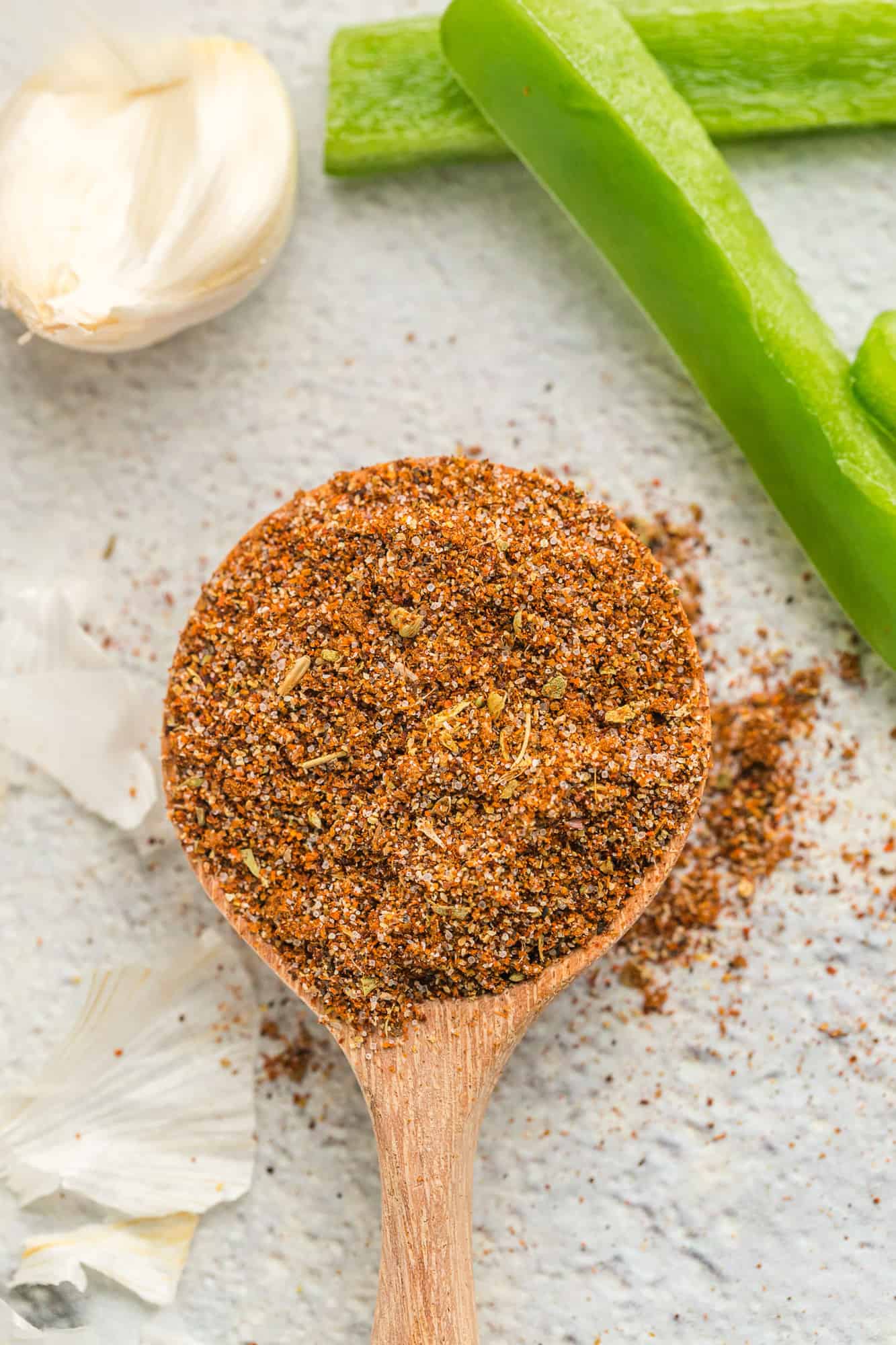 Fajita seasoning spilling off a small wooden spoon. 