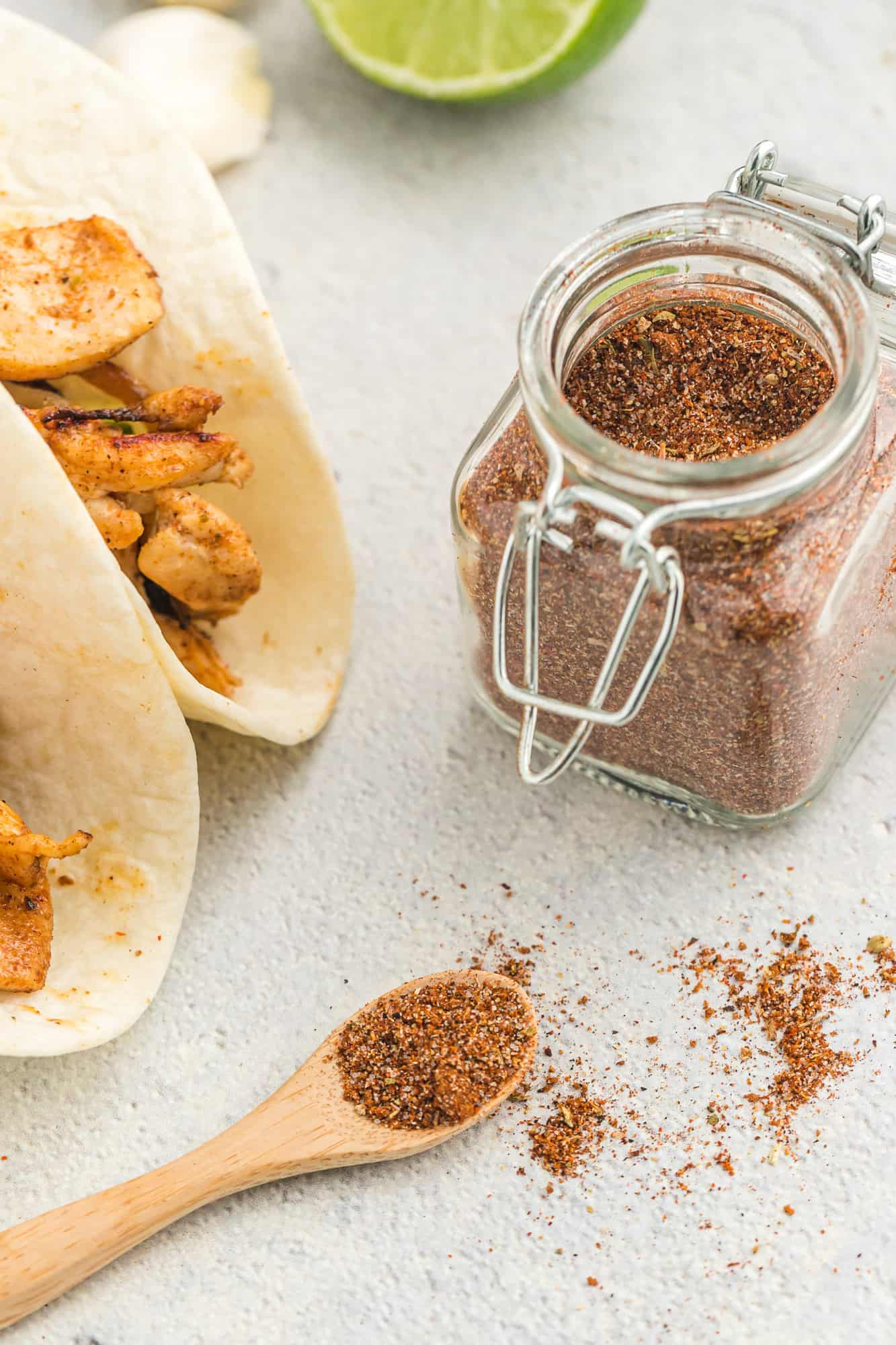 Fajitas in flour tortillas, jar of fajita seasoning next to them.