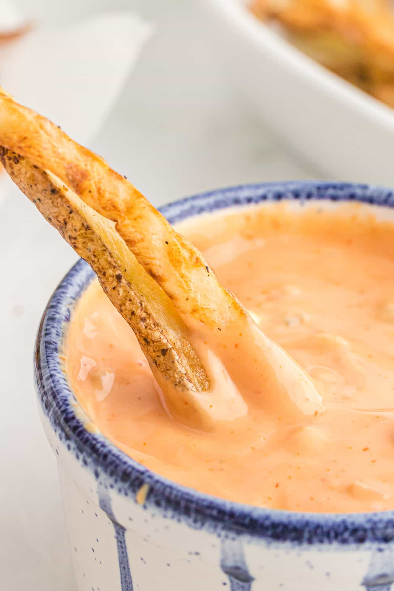 Fries being dipped into fry sauce.