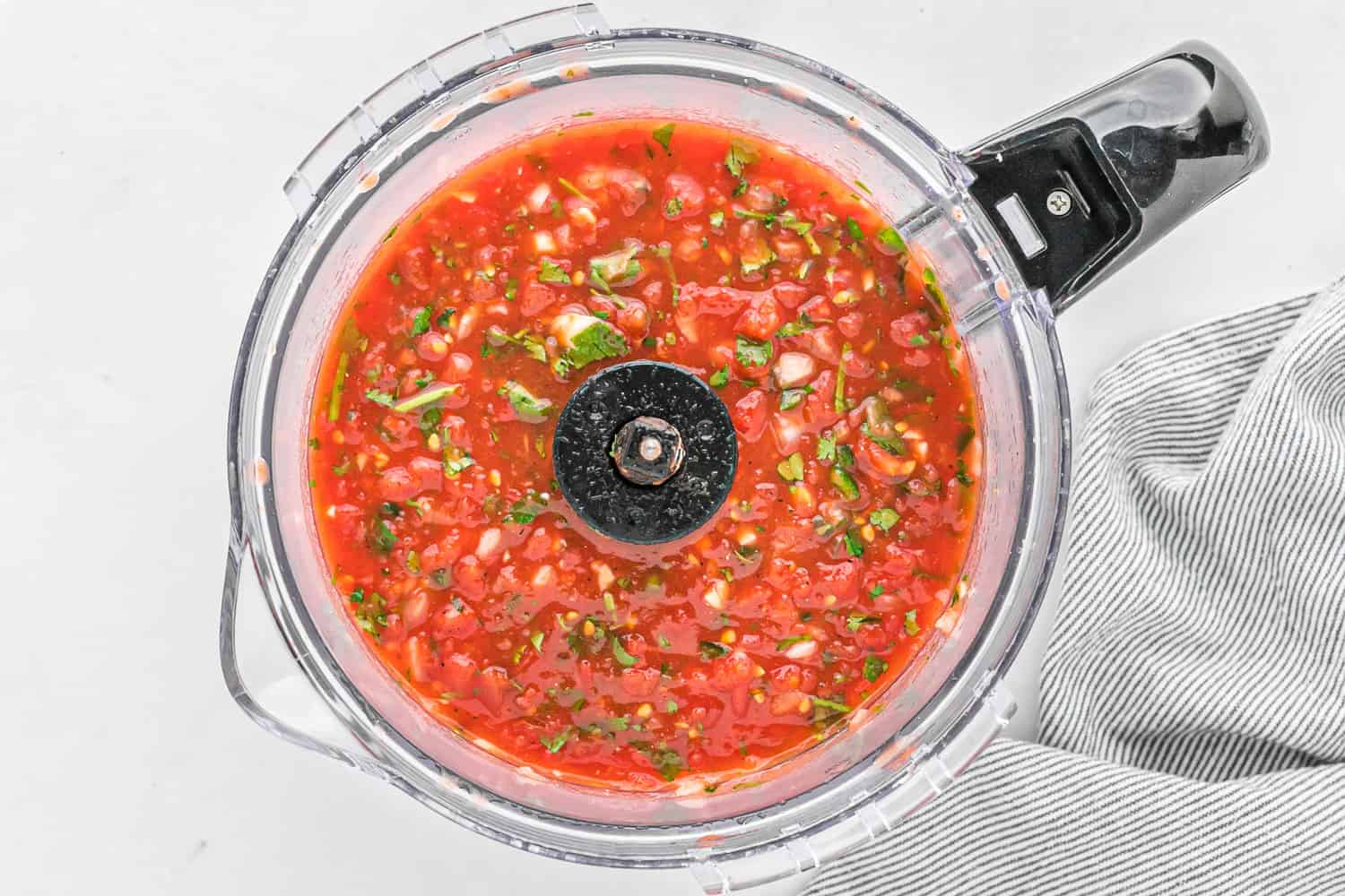 Salsa in a food processor with black handle.