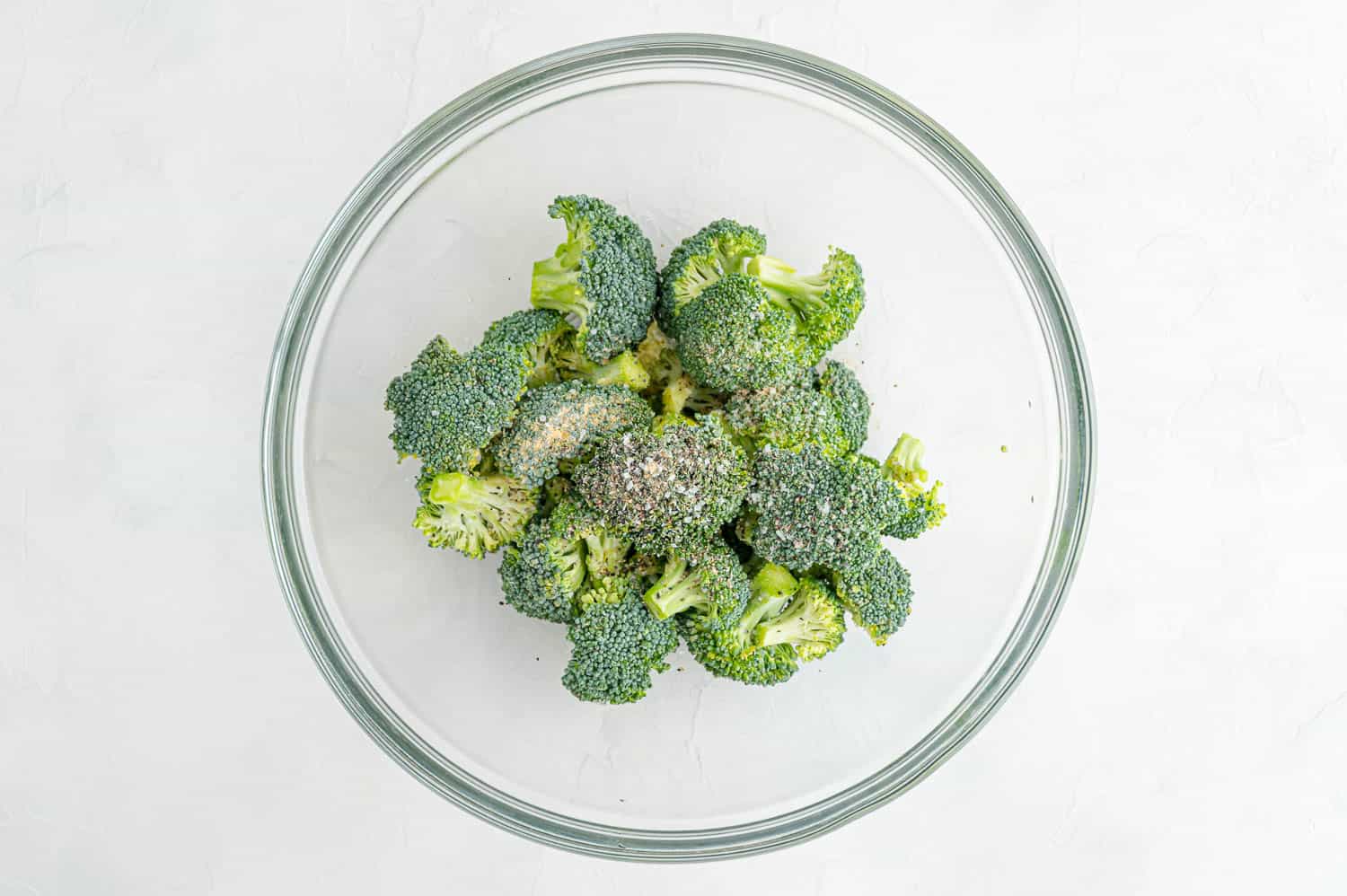 Broccoli in clear bowl with spices.