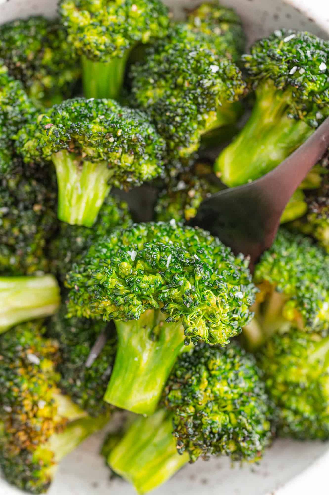 Pile of air fryer broccoli in a white bowl.