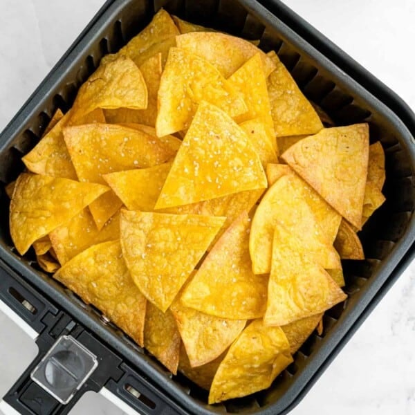 Air fryer basket filled with corn tortilla chips.