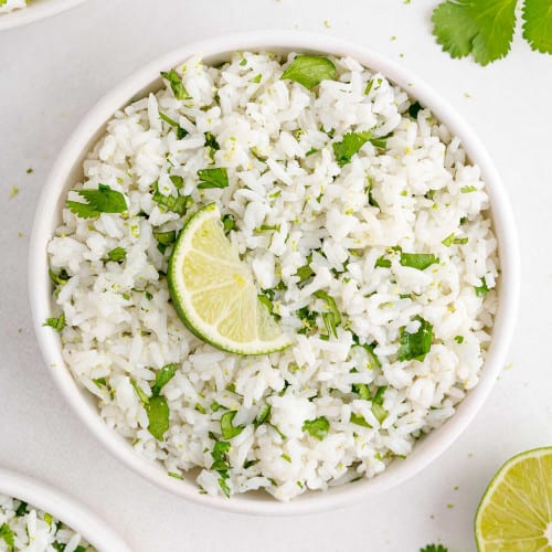 Cilantro lime rice in a bowl garnished with a lime wedge.