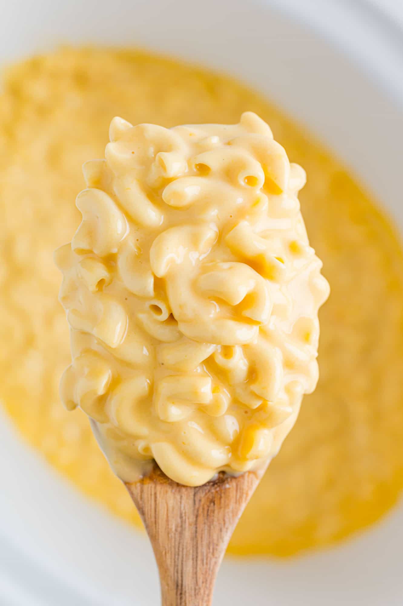 Large scoop of mac and cheese held over a crockpot.