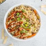 Overhead view of egg roll in a bowl drizzled with sriracha.