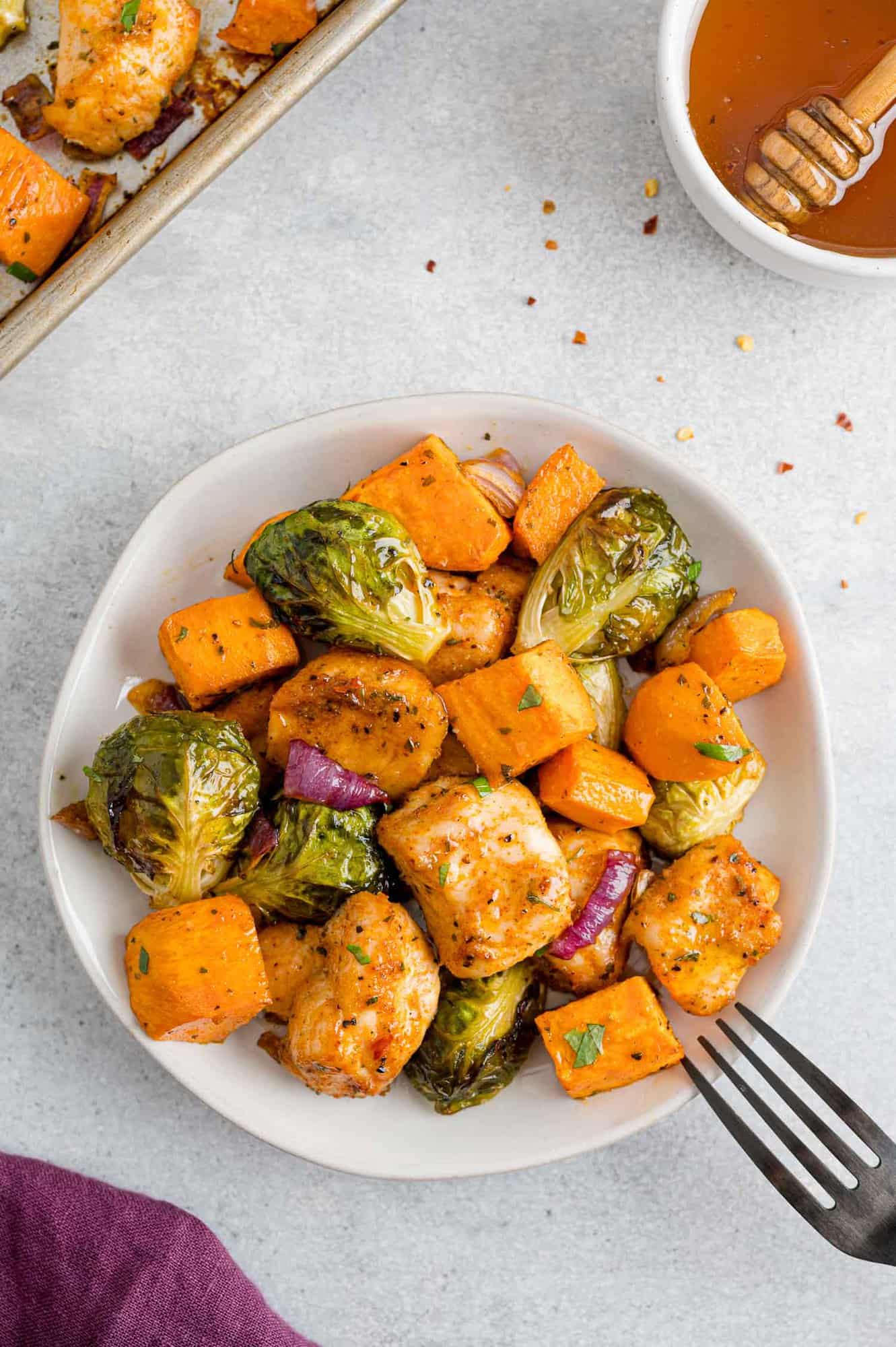 Chicken, brussels, and sweet potatoes on a small white plate.