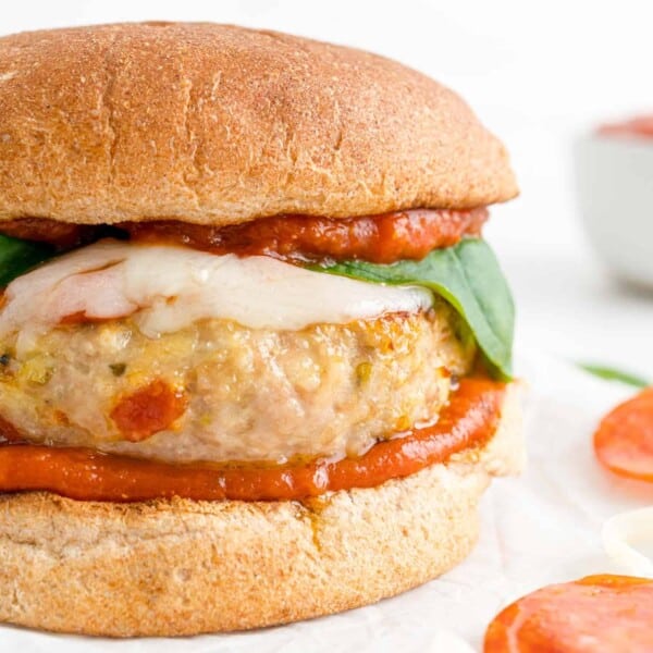 Pizza turkey burger on a whole wheat bun with basil.