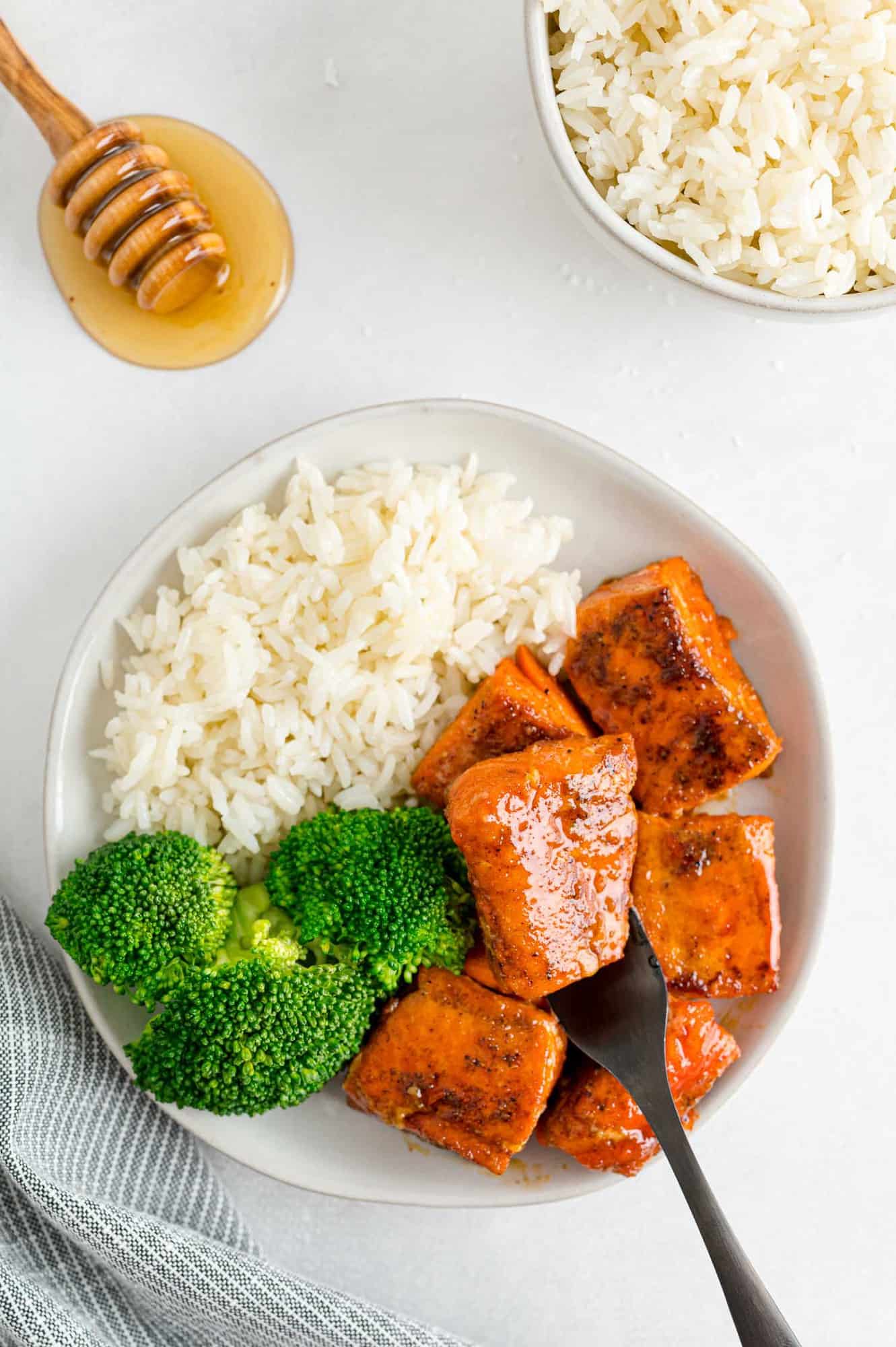 Salmon pieces on a plate with broccoli and rice.