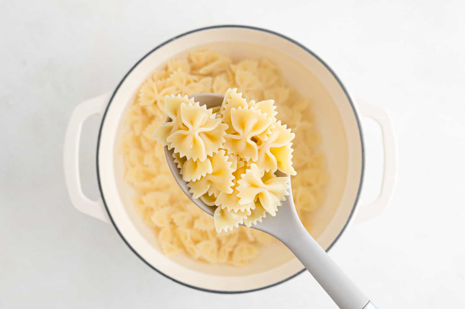 Cooked pasta in a spoon and in a pan.