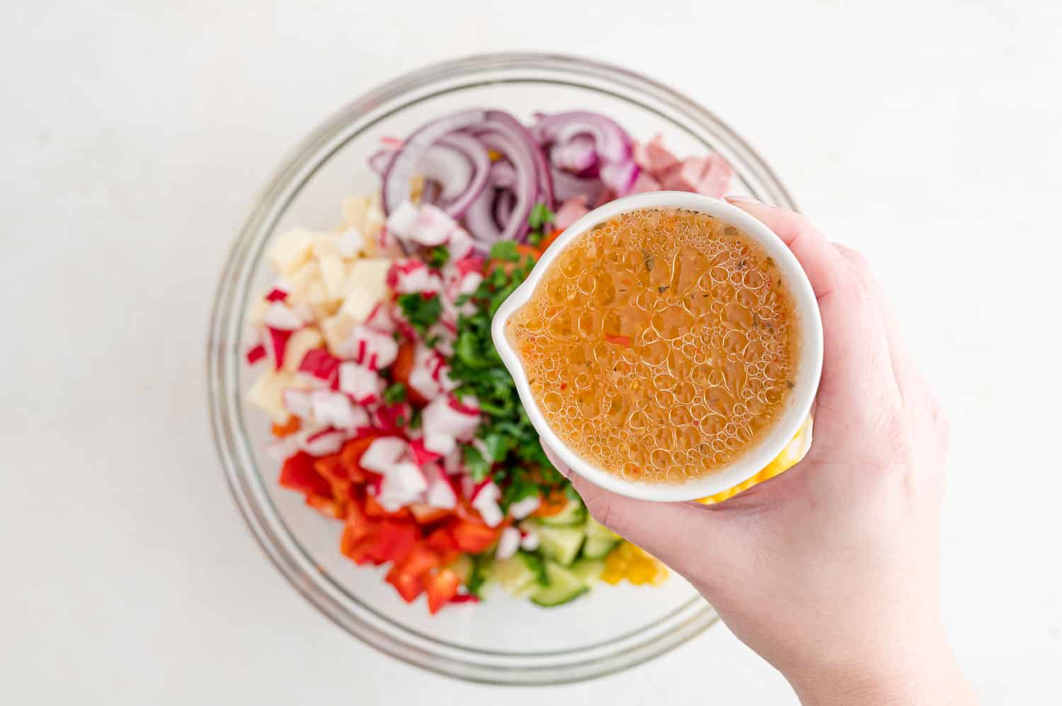 Dressing being added to pasta salad.